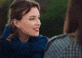 a woman wearing a blue scarf and red earrings is smiling