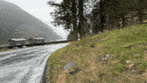a road going through a valley with a few houses in the background