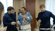 a group of men are standing in a room holding wine glasses and one of them is wearing a blue and white shirt
