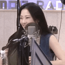a young woman is smiling in front of a microphone in a radio station .
