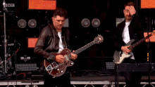 a man playing a guitar in front of a sign that says " bbc "
