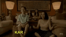 a group of people are sitting on a couch in a living room with the words kar-da-shi-an written above them .
