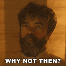 a man with a beard is smiling and says " why not then "