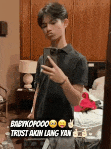 a young man is taking a selfie in front of a mirror in a hotel room .