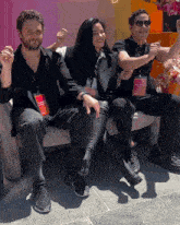 three people are sitting on a couch and one of them has a lanyard that says ' sydney ' on it