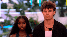 a man and a woman are standing next to each other and looking at something