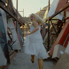 a woman in a white dress is walking through a pile of junk