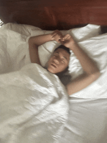 a blurry picture of a person sleeping on a bed with white sheets