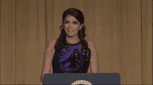 a woman is standing at a podium giving a speech and making a funny face .