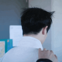 a close up of a man 's back with a person holding his shoulder .