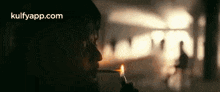 a man is smoking a cigarette in a dark room while holding a lighter .