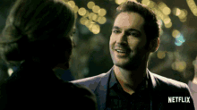 a man in a suit talks to a woman in a dark room with netflix written on the bottom