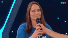 a woman in a blue shirt is being interviewed by a man in a microphone