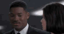 a man in a suit and tie is looking at a woman .