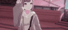 a girl in a hoodie is standing in front of a building and waving .