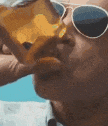 a close up of a person wearing sunglasses eating a sandwich