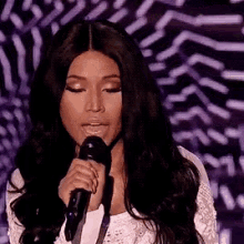 a woman with long hair is singing into a microphone on a stage .