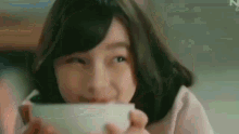 a close up of a woman drinking from a white cup .