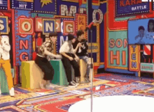 a group of people are sitting on blocks in front of a sign that says son hi .
