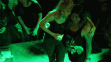 two women are hugging each other in a dark room with green lights behind them