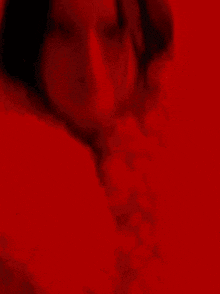 a woman is standing in front of a red wall and looking at the camera .