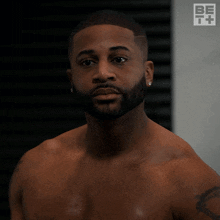 a shirtless man stands in front of a sign that says be