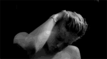 a black and white photo of a shirtless young man with blonde hair .