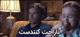 a man and a woman are sitting on a couch and the woman is crying while the man looks on .