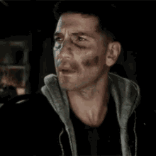 a close up of a man 's face with a black shirt and a hoodie .