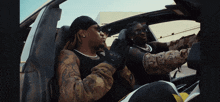two men are sitting in a car one wearing a bandana