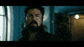a man with a beard is standing in a dark hallway
