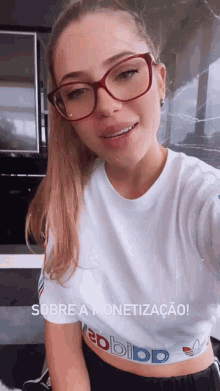 a woman wearing glasses and a crop top that says adidas