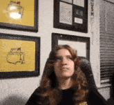 a woman sits in front of a wall with framed pictures of the 2007 masters on it