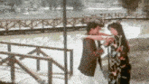 a man and woman are hugging each other in front of a lake .