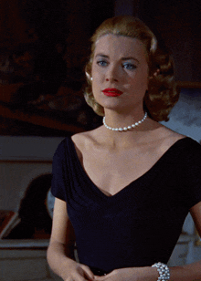 a woman wearing a pearl necklace and a black shirt