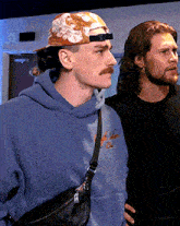 two men are standing next to each other one wearing a hoodie that says ' a ' on it