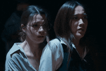 two women are standing next to each other in the dark