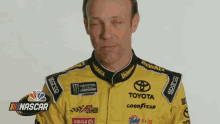 a man wearing a yellow toyota racing suit is making a funny face
