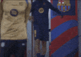 a man in a blue shirt is standing in front of a wall with a fcb logo on it