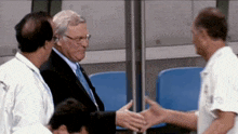 a man in a suit is shaking hands with another man in a white shirt