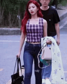 a woman with red hair is walking down the street next to a man holding a jacket .