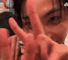 a close up of a person 's face making a peace sign with their fingers .