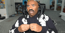 a bald man wearing headphones and a kappa sweatshirt looks surprised