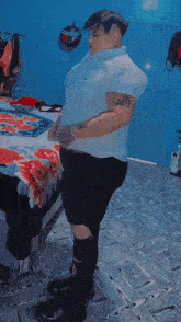 a man in a white shirt and black shorts is dancing in front of a bed that has a floral blanket on it
