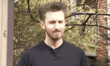 a man with a beard is wearing a black shirt and a microphone on his neck .