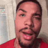 a close up of a man 's face with a beard and a red shirt .