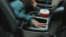 a person in a car reaching for a cup of soda