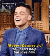 a man in a suit is laughing while talking to robert downey jr. on the tonight show .