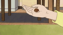 a hand holding a small piece of chocolate in front of a table