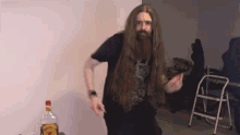 a man with long hair and a beard is standing in front of a bottle of jim beam